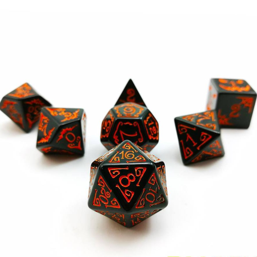 A set of seven polyhedral dice placed in an arrow on a white background. Black acrylic Filigree designs around numbers. Numbered with orange ink.